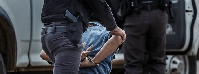 Police arresting a man who is kneeling